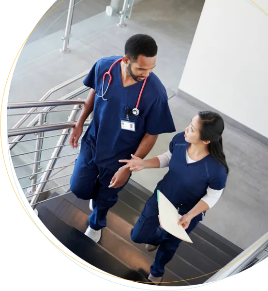 A male and female doctor talking while walking up the hospital stairs