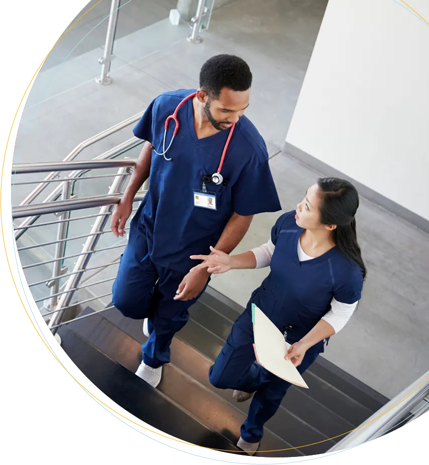 A male and female doctor talking while walking up the hospital stairs