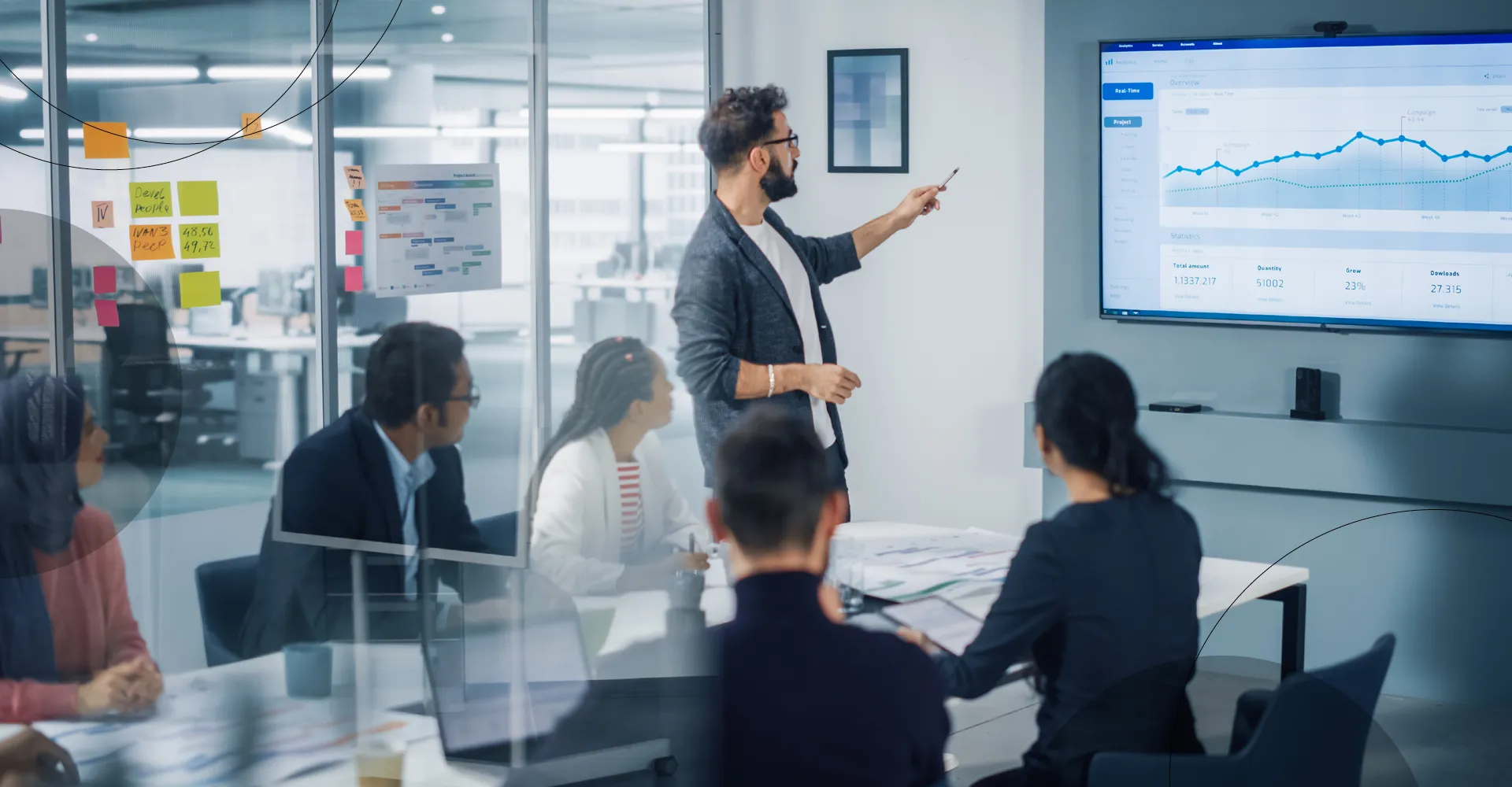 photo of a man standing presenting charts in a meeting room with other people